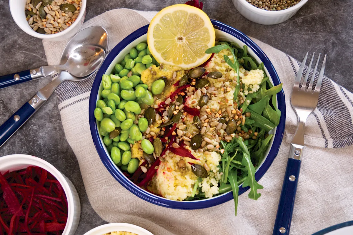 Eine klassische Bowl auf Rucolabasis mit Couscous und Hummus.