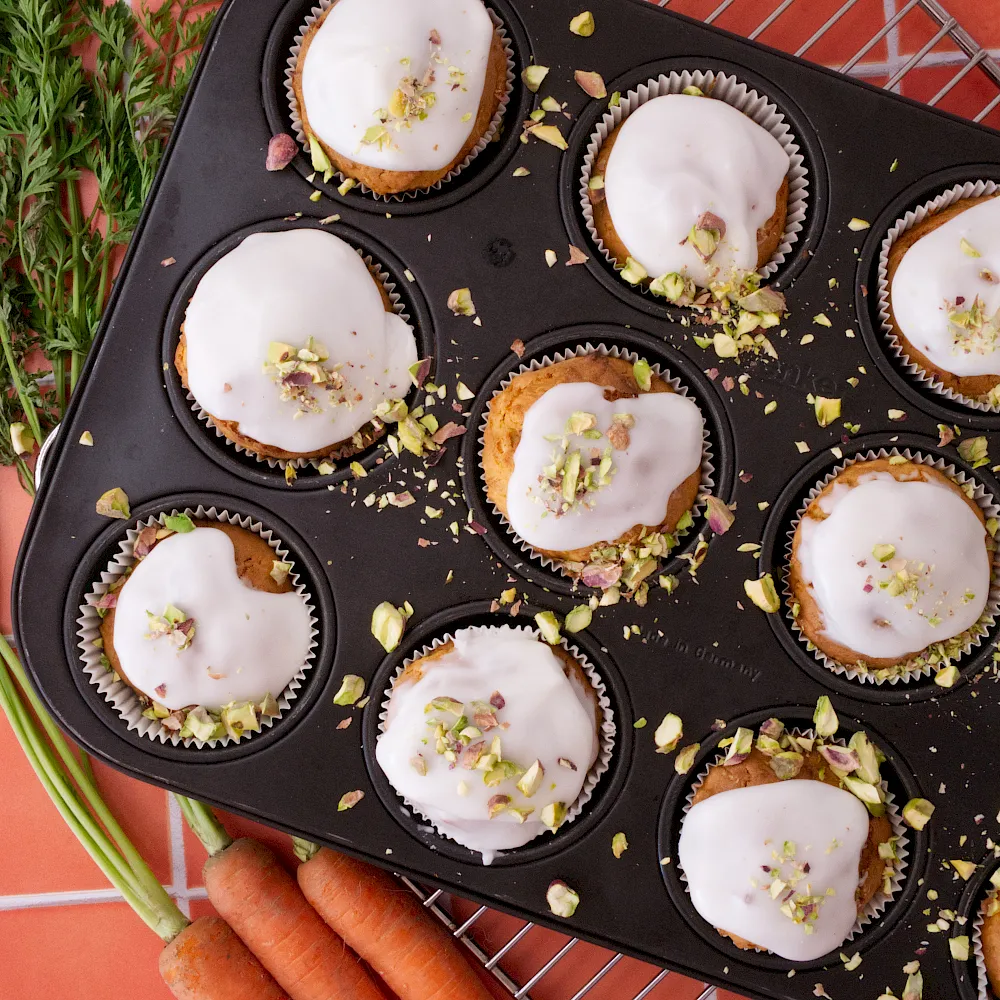 Saftige Karottenmuffins mit feiner Zitronenglasur und einem zarten Crunch aus Pistazien